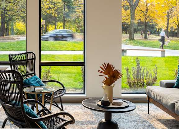 a living room with chairs and a table in front of a window