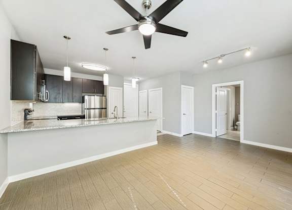 A spacious kitchen with a ceiling fan and lighting fixtures.