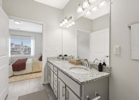 A bathroom with a large mirror, a sink, and a window.