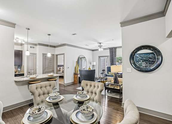 A modern dining room with a glass table and white chairs.
