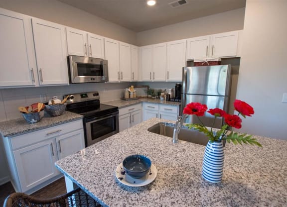 a kitchen with white cabinets and a counter with red roses