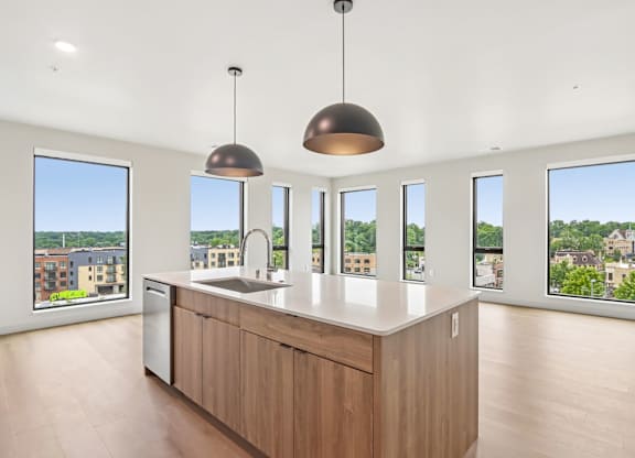 A kitchen with a large island and pendant lights.