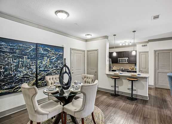 A dining room with a table set for two and a cityscape on the wall.