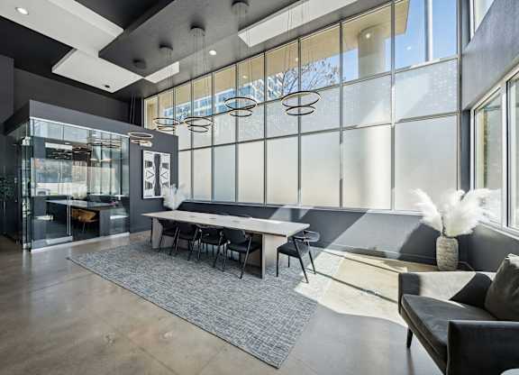 A modern living room with a glass wall and a grey sofa.