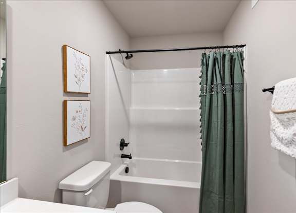 A white toilet sits next to a white bathtub in a small bathroom.