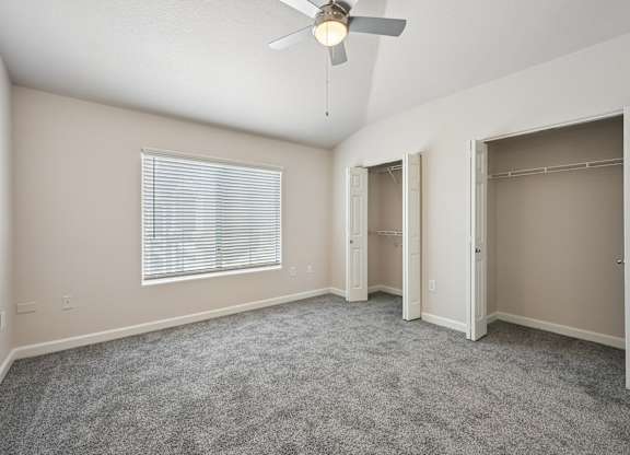 A room with a ceiling fan and carpeted floor.