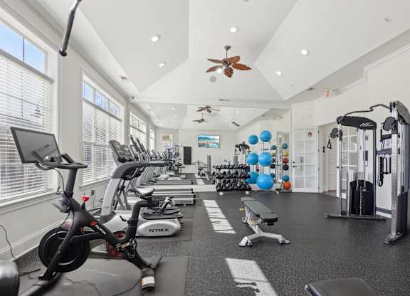 A gym with a variety of exercise equipment including treadmills, stationary bikes, and weight machines.
