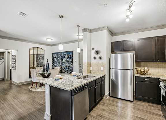 A kitchen with a stainless steel refrigerator and black cabinets.