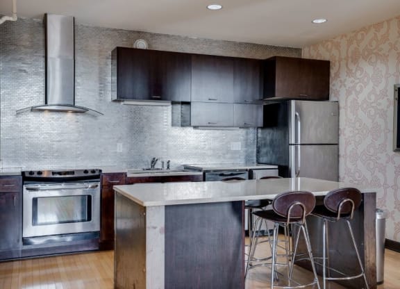 a kitchen with stainless steel appliances and a bar with three stools C&E Living in St Paul, MN