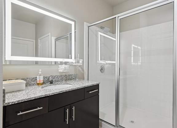 A bathroom with a sink, mirror, and shower.