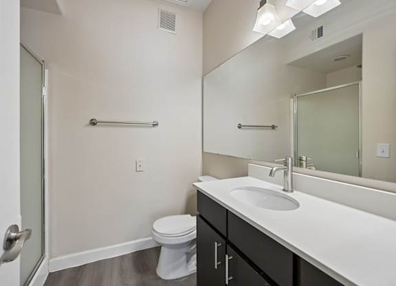 A bathroom with a toilet, sink, and mirror.