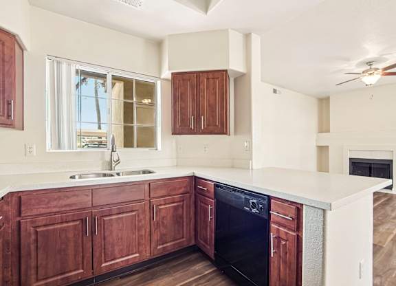 A kitchen with wooden cabinets and a black dishwasher.