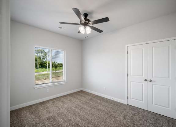 A room with a ceiling fan and a window with blinds.