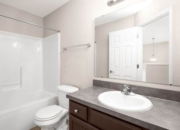 A white toilet sits next to a white bathtub in a bathroom.