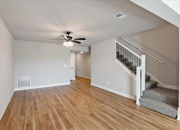 A room with a staircase and a ceiling fan.