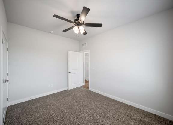 A room with a ceiling fan and carpeted floor.