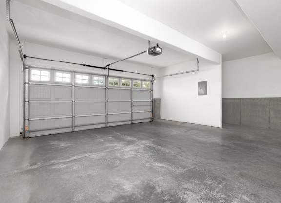 A large, empty garage with a concrete floor and white walls.