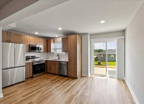 A modern kitchen with wooden floors and stainless steel appliances.
