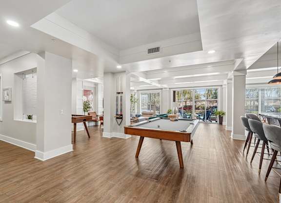 A room with a pool table and chairs.