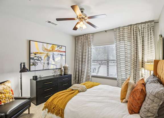 A bedroom with a bed, dresser, and a painting on the wall.