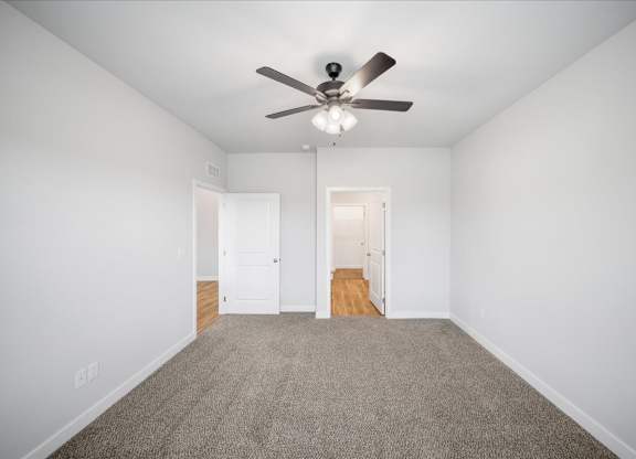 A room with a ceiling fan and carpeted floor.