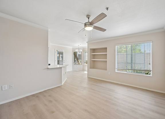 A room with a ceiling fan and a window with blinds.