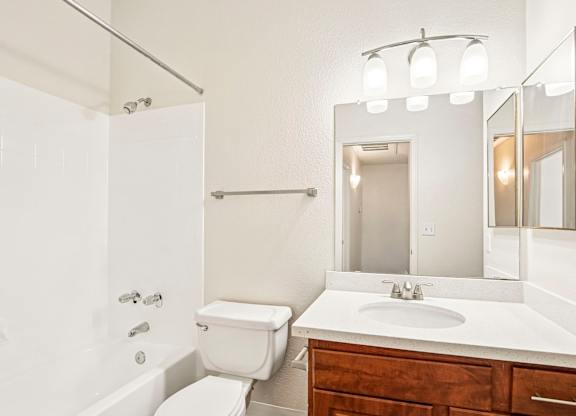 A white bathroom with a toilet, sink, and mirror.