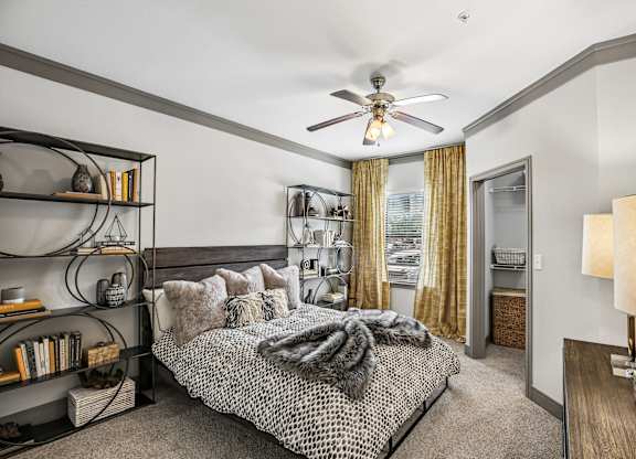 A bedroom with a bed, a ceiling fan, and a bookshelf.