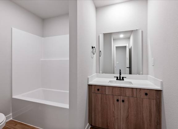 A bathroom with a white sink and a wooden cabinet.