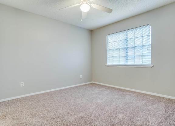 an empty room with a window and a ceiling fan