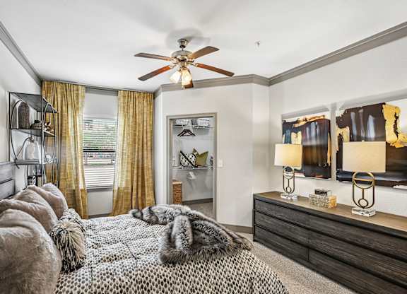 A bedroom with a bed covered in a fur throw and a ceiling fan.