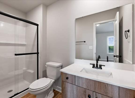 A modern bathroom with a toilet, sink, and mirror.