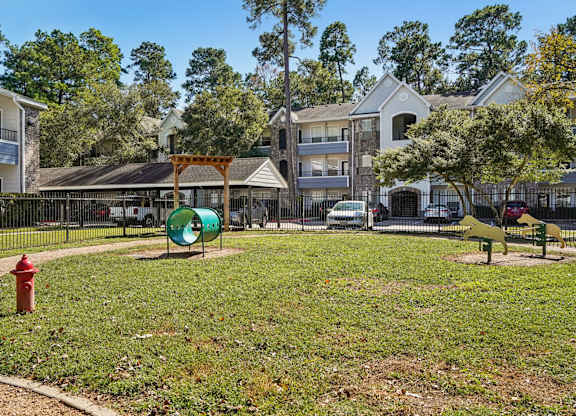 A park with a red fire hydrant and a green playground.