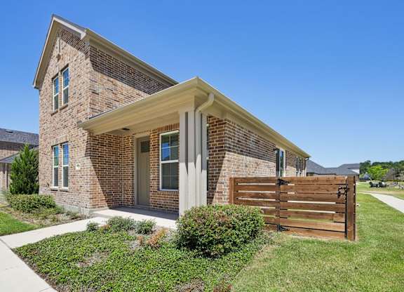 A house with a brown brick exterior and a wooden fence.