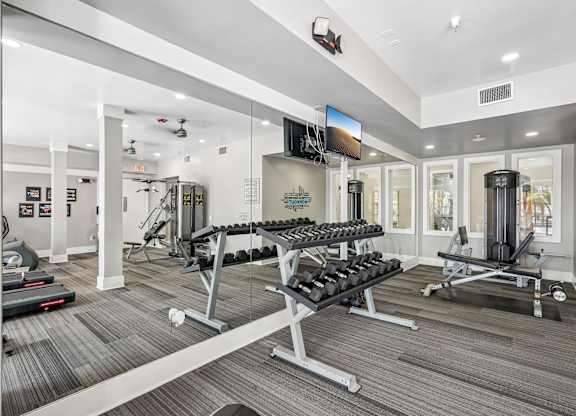 A gym with a variety of equipment including treadmills, weights, and exercise machines.