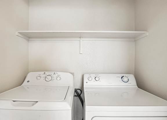 Two white washing machines in a small laundry room.