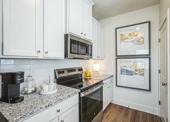 A kitchen with a granite countertop and white cabinets.