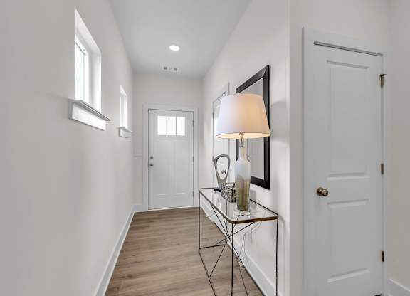 A hallway with a table and a lamp.