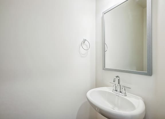 A white sink in a bathroom with a mirror above it.
