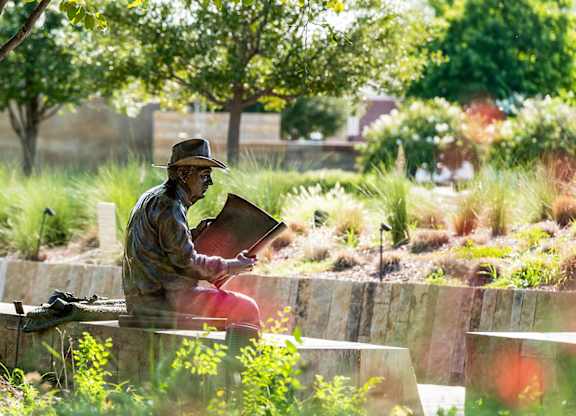 A statue of a man sitting and reading a book.