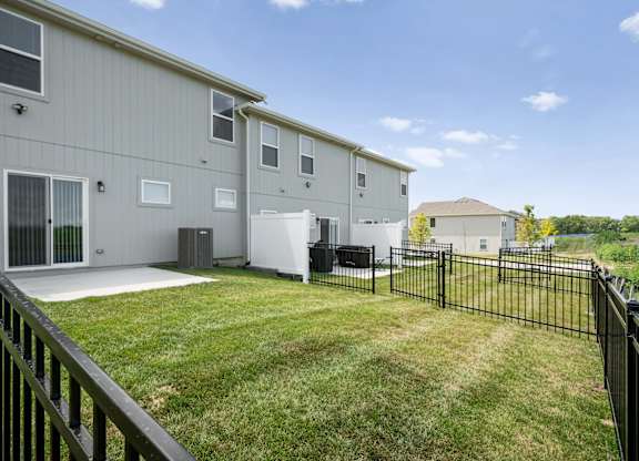 Apartment complex with a black fence and green grass.
