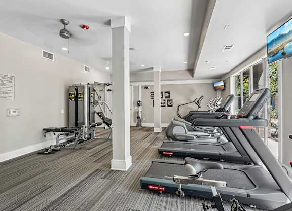 A gym with treadmills, weights, and exercise equipment.