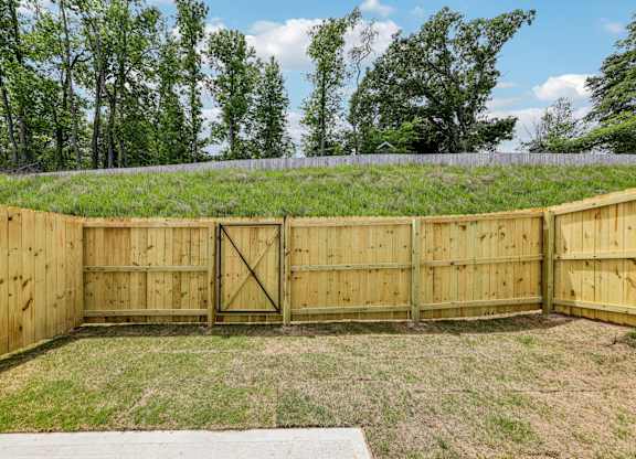 A wooden fence encloses a grassy area with a gate in the middle.
