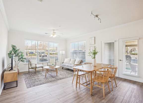 A living room with a white couch, wooden chairs, and a television.