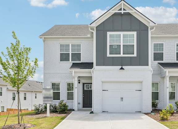 A white house with a black garage door in front.