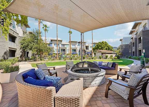 A patio with a fire pit and chairs under a canopy.