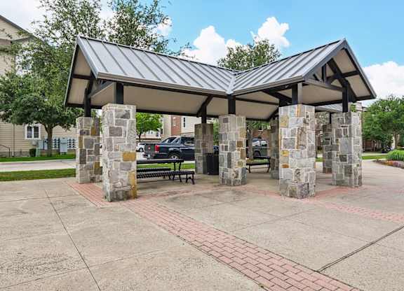 A covered walkway with a metal roof and stone pillars.