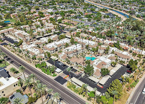 A bird's eye view of a residential area with houses, roads, and palm trees.
