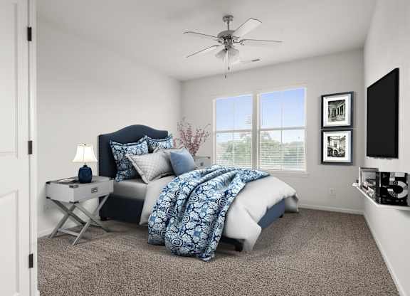 A bedroom with a bed, a fan, and a window.