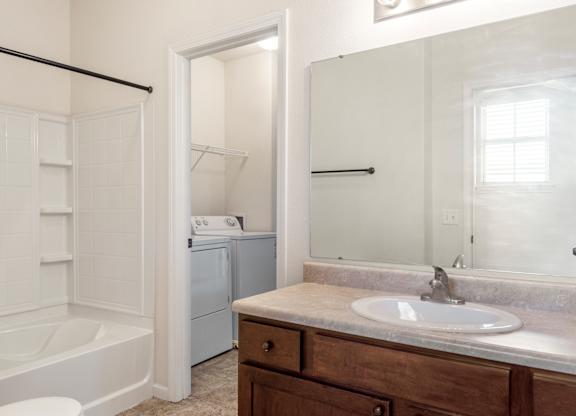 A white bathroom with a tub, sink, and mirror.